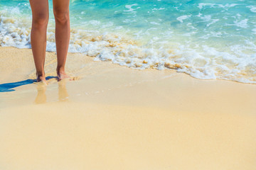 Closeup of female legs on tropical beach. Women's legs on the sa