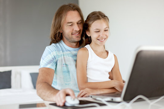 Dad with his daughter using laptop.