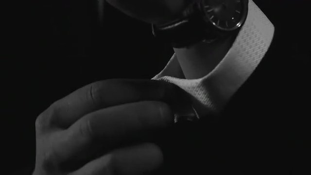 Close up of businessman hand fastening cufflinks on his sleeve