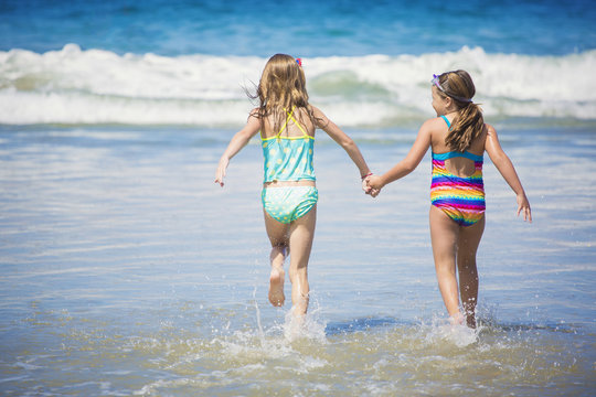 Cute little girls playing at the beach together during summer vacation 