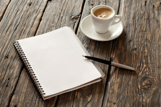 open notebook with blank pages and pen with coffee espresso
