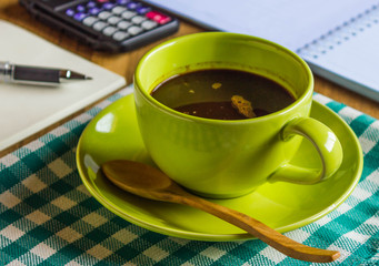 Office table with notepad and pen, calculator, cup of coffee and