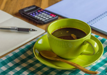 Office table with notepad and pen, calculator, cup of coffee and