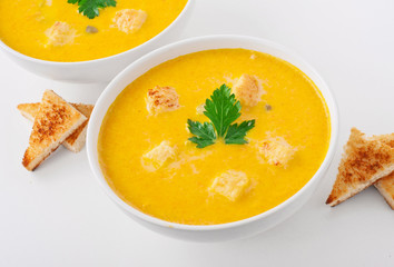 Bowl of squash soup with croutons and parsley leaf