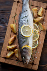 Top view of baked seabass served with potato wedges, close-up