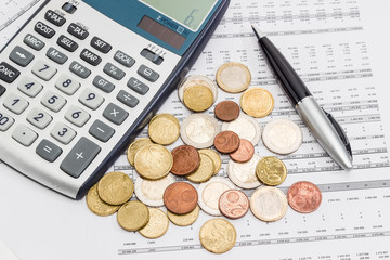 Euro coins, pen and calculator fragment on the data table