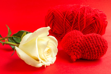 Cream rose with red heart crochet on red background