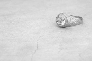 Closeup old diamond ring on blurred cement floor background in black and white tone