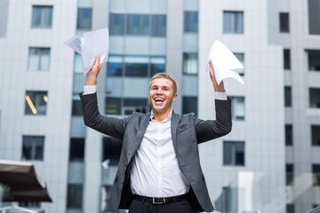 I did it happy young businessman in shirt and tie holding paper and keeping arms raised