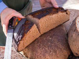 Male hands slicing rye bread