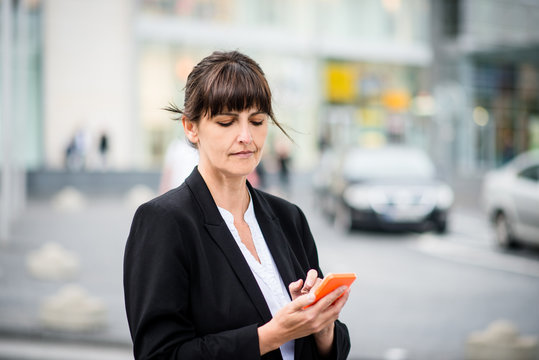 Senior business woman with phone in street