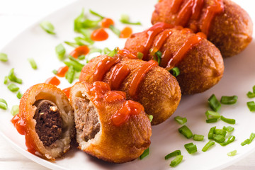 rissole stuffed with meat covered with sauce and sliced green onions