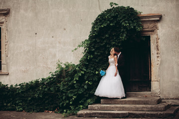 Happy wedding couple hugging and smiling each other on the background gorgeous plants in castle © olegparylyak