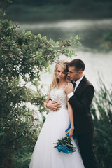 Romantic wedding couple, man and wife, posing near beautiful lake