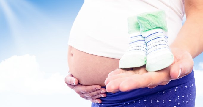 Composite image of pregnant woman holding baby shoes 