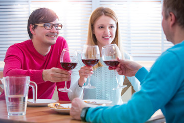 Group Of Young People Enjoying Meal and drinking wine In Restaurant. Friends Dining, celebrating and Hanging out. Hands toasting. 