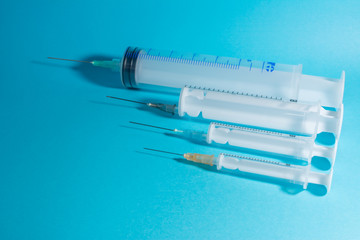 syringes on a blue background, parallel, sorted by size - obrazy, fototapety, plakaty