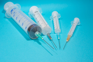 syringes on a blue background, round, sorted by size - obrazy, fototapety, plakaty