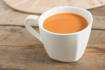 Hot milk tea in a white cup. Selective focus.
