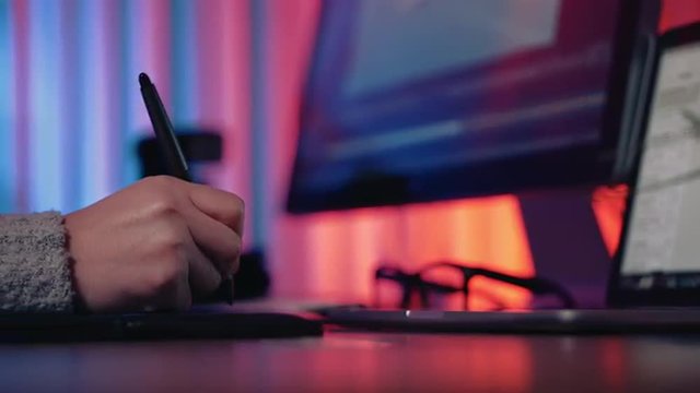 Dolly shot of Caucasian female graphic artist working at her desk using digitizer