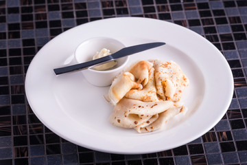 Closeup dish with pancakes and knife and butter on table