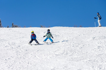 Two young children, siblings brothers, skiing in Austrian mounta