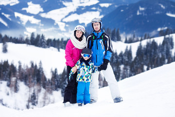 Young happy family with one child, skiing in the mountains