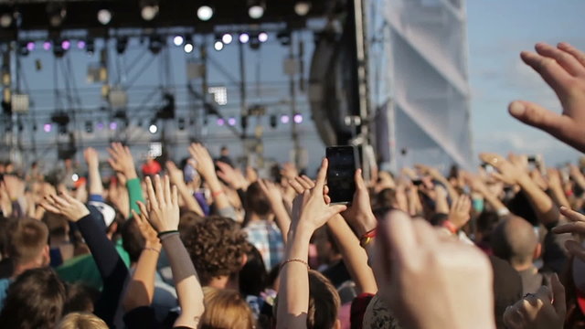 People raise their hands up and applaud at a concert. 