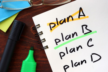 Cross plan A, underline plan B concept  written in a notebook on a wooden table.