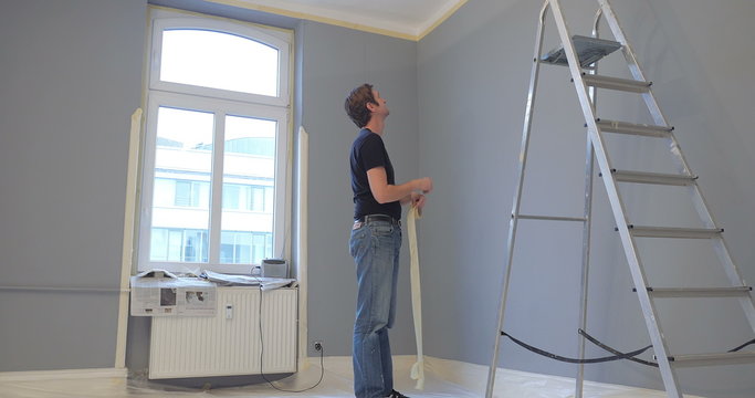 man showing frustration with his work in new appartment. throwing ribbon band on the wall and rsignating from his work