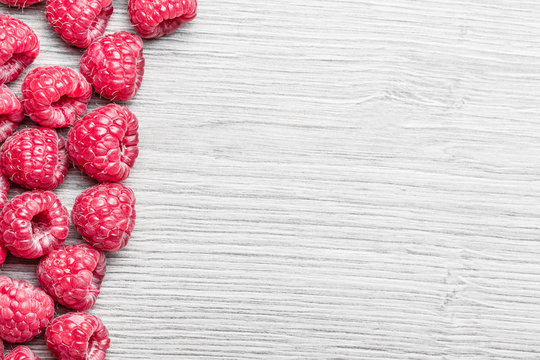 Raspberries on gray wooden table background.