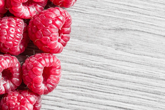 Raspberries on gray wooden table background.