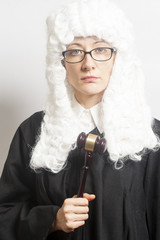 Female judge wearing a wig and Back mantle with eyeglasses holdi