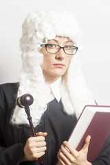 Female judge wearing a wig and Back mantle with eyeglasses holdi