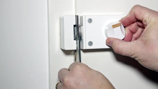 Mann bedient einen Sperrriegel an der Wohnungst&uuml;r - Man handled a locking bolt on a door