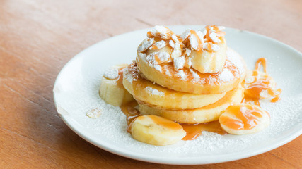 Banana pancake with caramel and powdered sugar on wooden table.