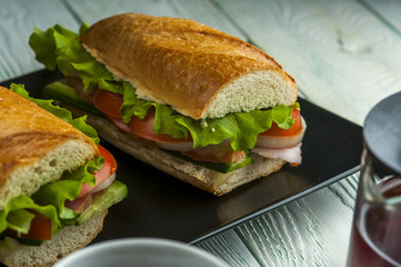 Tasty sandwiches with ham, vegetables and lettuce on black plate. Fast food. Focus on sandwich.
