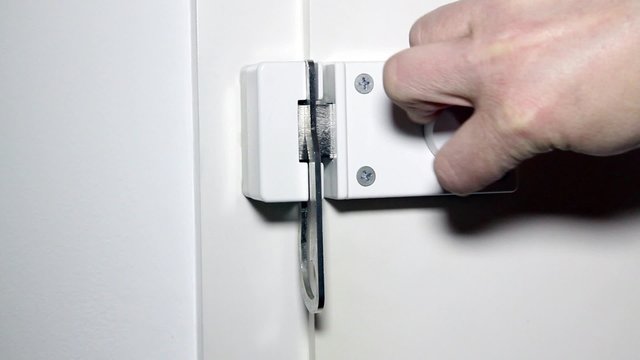 Mann schlie&szlig;t einen Sperrriegel an der Haust&uuml;r - Man closed a locking bolt on a door at home