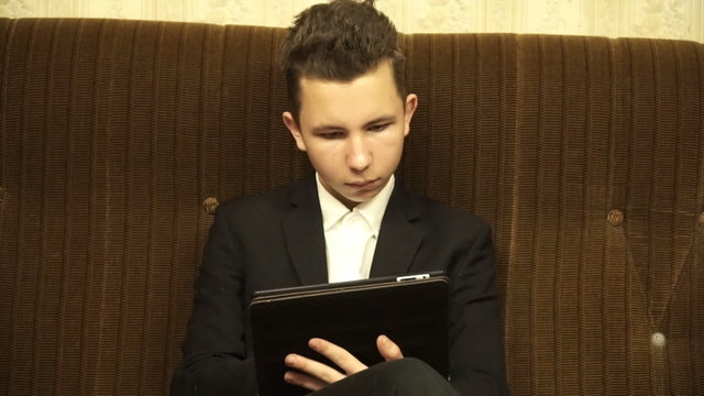 teenager sitting on the sofa and using tablet