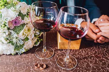 Hands groom on a table with glasses and wedding rings
