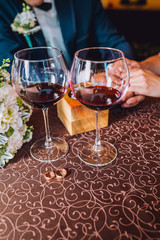 Hands groom on a table with glasses and wedding rings