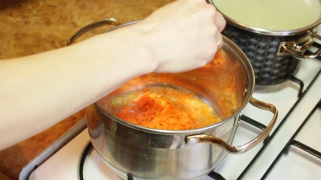 Braise the carrots in a saucepan. Тушит и перемешивает морковь лопаткой.