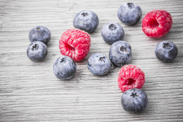 Blueberries and raspberries on gray wood.
