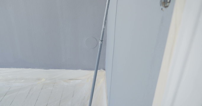 paint roller leaning on wall in room of new appartment. camera panning from bottom to top