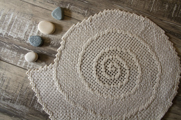 Fototapeta na wymiar Hardanger embroidery napkin with stones on the wood table.