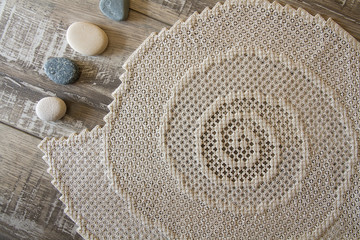 Hardanger embroidery napkin with stones on the wood table.