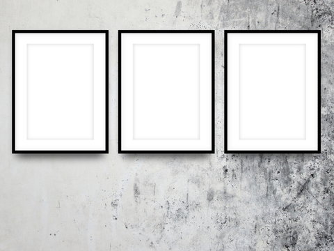 Close-up of three black picture frames on stained concrete wall background