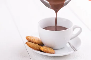 Photo sur Plexiglas Chocolat Verser un délicieux chocolat chaud dans une tasse blanche sur la table.