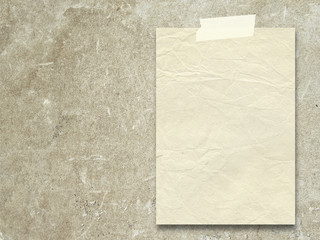 Close-up of one vintage paper sheet with tape on rough brown plaster wall background