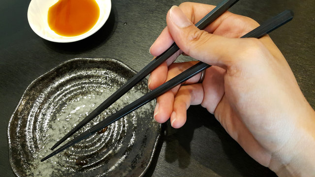 Hand holding a pair of chopsticks
